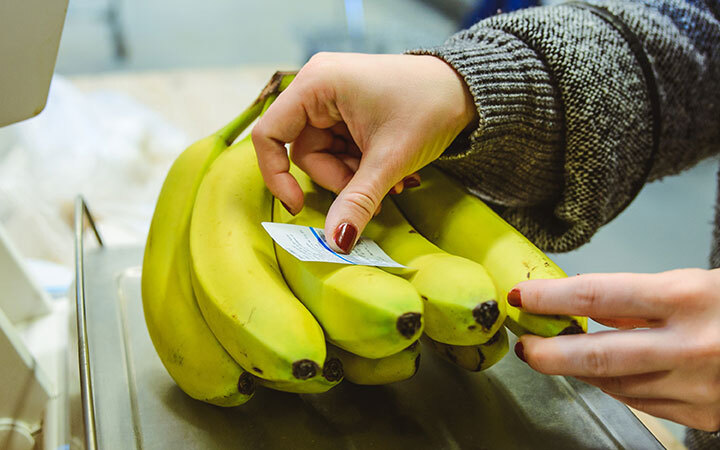 Bananen werden mit Etikett beklebt auf einer Waage