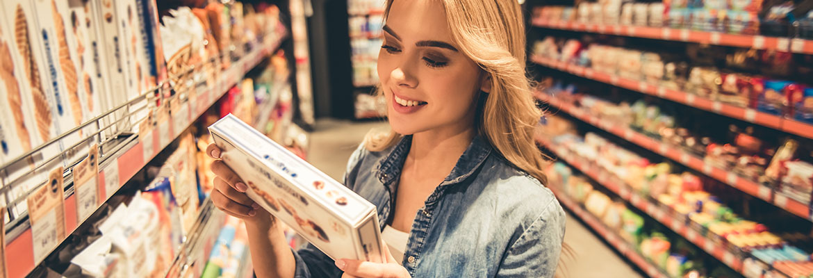 Frau welche im Supermarkt Rückseite einer Lebensmittelverpackung durchliest