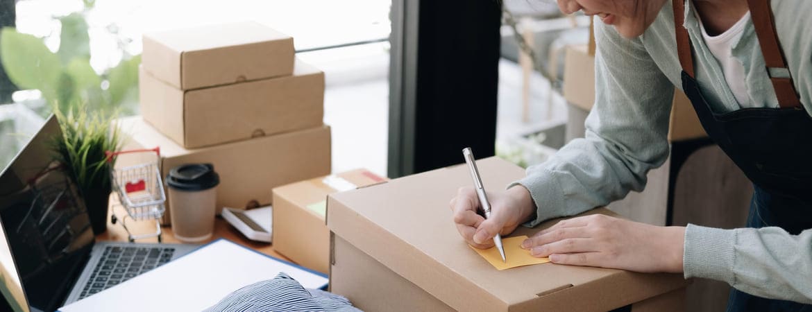 Frau beschriftet Pakete für den Versand