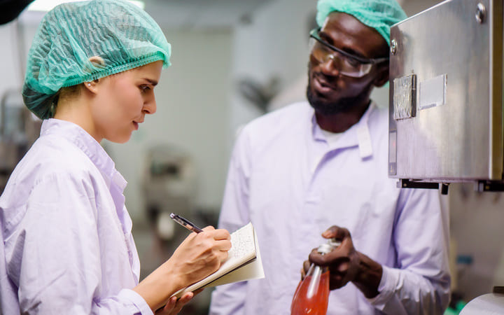 Zwei Mitarbeiter in der Lebensmittelkontrolle unterhalten sich über HACCP 