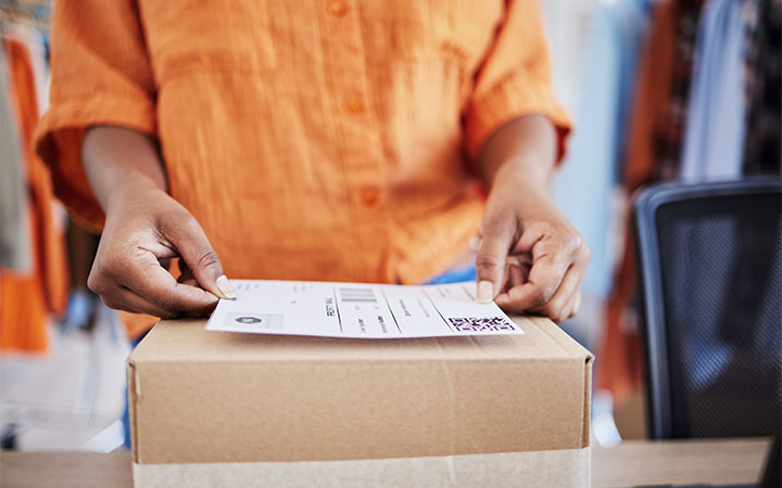 Frau beklebt Paket von Hand 