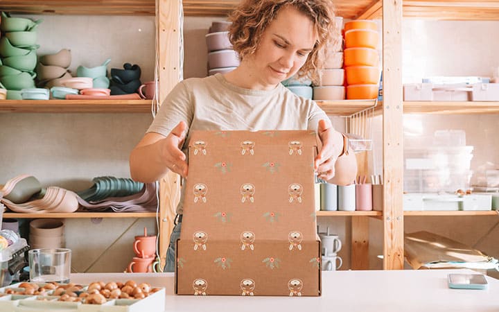 Frau verpackt Produkte in bedrucktem Faltkarton