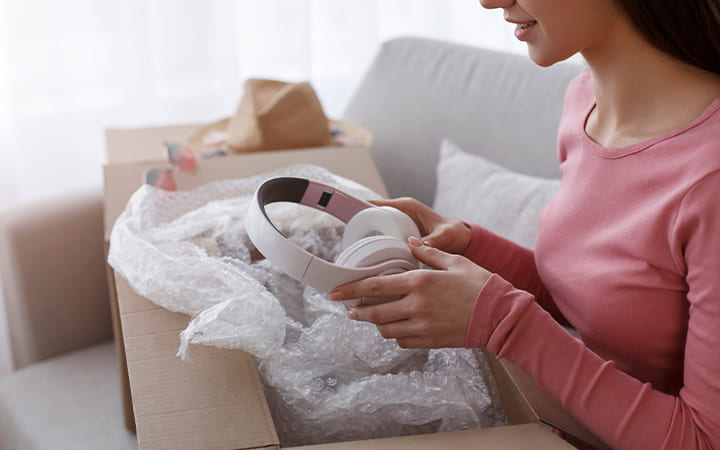 Frau packt Kopfhörer aus Versandkarton aus Frau packt Kopfhörer aus Versandkarton aus