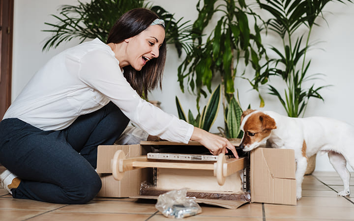 Karton wird ausgepackt von glücklicher Frau Karton wird ausgepackt von glücklicher Frau