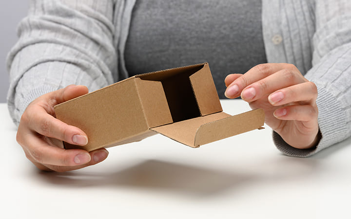 Frau hält Faltschachtel mit Einstecklasche Frau hält Faltschachtel mit Einstecklasche