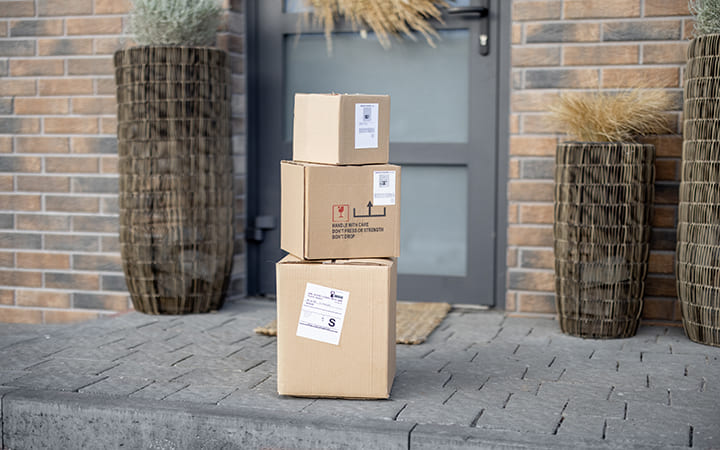 Versandkartons aufeinandergestapelt vor Haustür Versandkartons aufeinandergestapelt vor Haustür