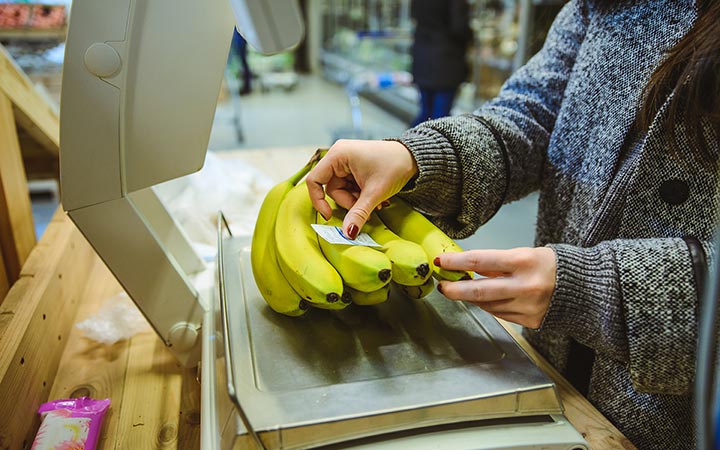 Frau klebt nach dem Wiegen Etikett auf Bananen